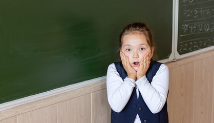 A first grader stands at the blackboard and is very scared. Back to school.