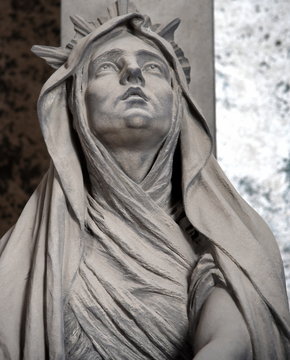 Skulptur einer zum Himmel schauenden Frau auf einem Friedhof