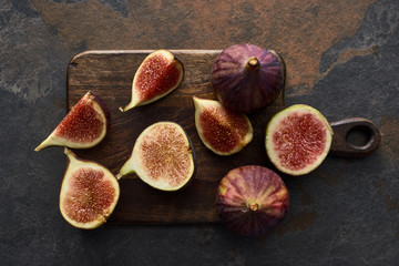 top view of ripe cut delicious figs on cutting board on stone background