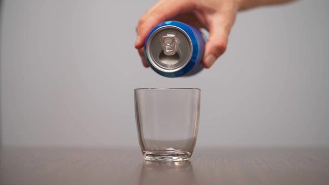 Man pouring sugar into glass from blue soda can. Sugar-sweetened beverages. Isolated, on white background