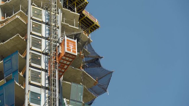 Industrial elevator on outside of skyscraper during new construction on construction site going up the new building