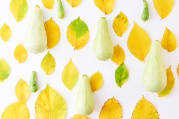 Flat lay pattern with colorful autumn leaves and pumpkins on a white background