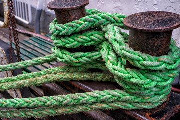 Fototapeta na wymiar Green twisted marine rope wraped around metal poles