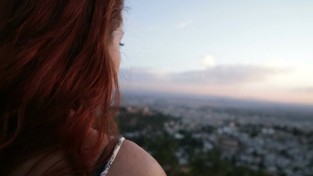young redhead woman contemplating the city at sunset