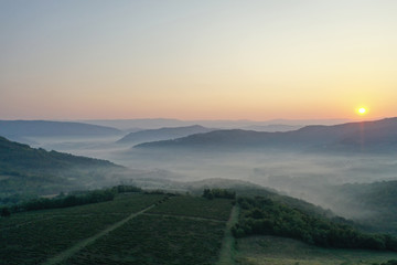 Fototapeta na wymiar Mountain landscape. Sunrise over the mountains. The valleys are covered with fog. The view from the top. Copy space.
