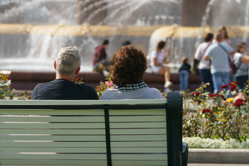 Pair of man and woman resting on the bench in the park near the fountain of the Friendship of...