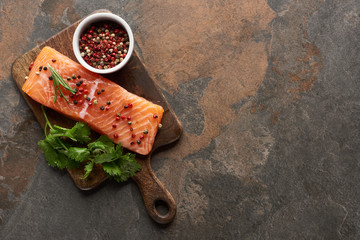 top view of raw fresh salmon with peppercorns, parsley on wooden cutting board