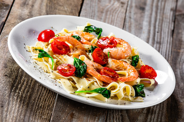 Shrimps with pasta tagliatelle with spinach and tomatoes