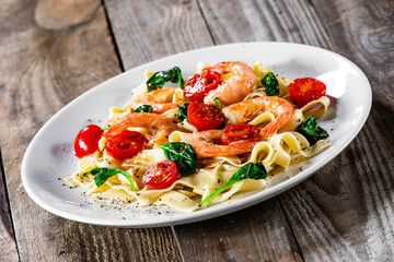 Shrimps with pasta tagliatelle with spinach and tomatoes