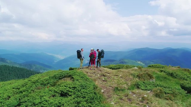 The four active people standing on the mountain with a beautiful landscape
