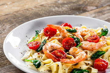 Shrimps with pasta tagliatelle with spinach and tomatoes