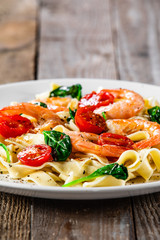 Shrimps with pasta tagliatelle with spinach and tomatoes