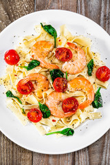 Shrimps with pasta tagliatelle with spinach and tomatoes