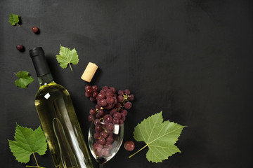 Flat-lay of a bottle, wine glasses, fresh grapes and cork on black background, top view, copy space. Wine bar, winery, wine tasting concept