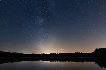reflection of the milky way on the smooth surface of a small lake