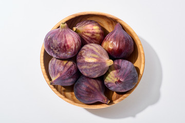 top view of ripe whole delicious figs in wooden bowl on white background