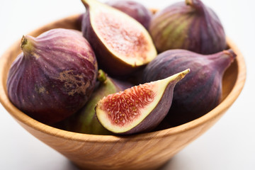 close up view of ripe delicious figs in wooden bowl on white background