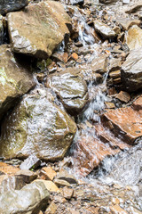 Source flowing between stones in the mountains.
