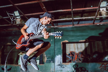 Musician playing electric guitar in abandoned place