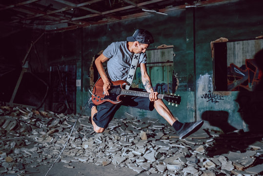 Musician playing electric guitar in abandoned place