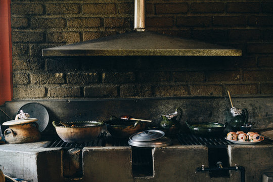 Old grimy stone heater with shabby pots and ventilation system over brick wall in daylight