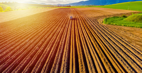 Farmer in tractor preparing land with seedbed cultivator in farmlands. Tractor plows a field....