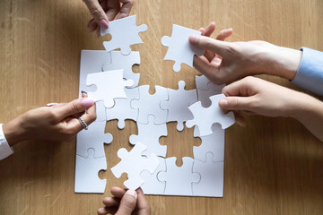 Top view of diverse people assemble jigsaw looking for solution