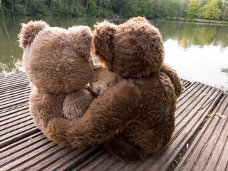 Bärenfamilie, Vater, Mutter und Kind sitzen an einem Sommerabend auf einen Bootssteg.
