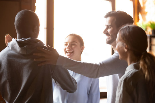 Smiling diverse friends greeting in cafe, welcoming at meeting