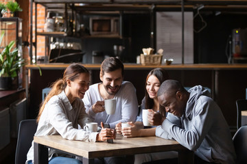 Diverse friends having fun in cafe, looking at smartphone screen