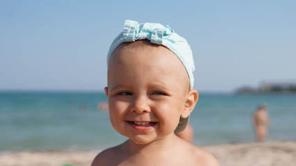 Close-up portrait of happy smiling child in blue cap standing on sea beach
