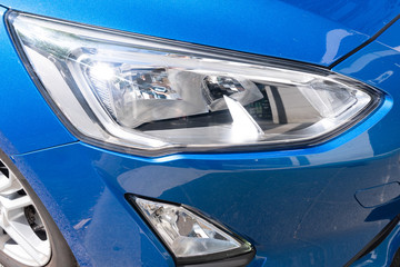 headlight detail of modern blue luxury car with projector lens for low high fog beam