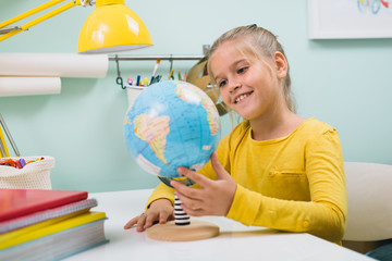 girl looking at geographic globe sitting table in her room