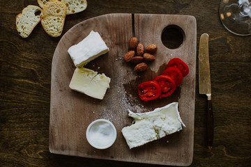 gourmet fancy charcuterie with cheese, nuts, tomatoes and cutting board