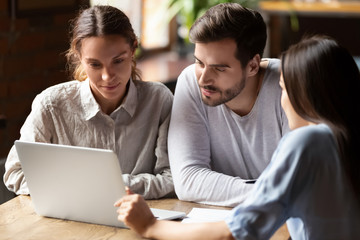 Realtor or insurance broker consulting young couple in cafe