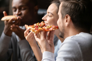 Close up happy diverse friends eating pizza in cafe together
