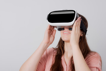 Woman using VR device holding in both hands smiling and looking up.