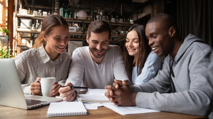 Diverse friends analyzing documents together, doing homework in cafe