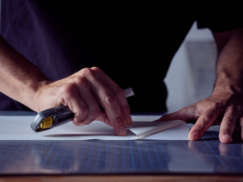 Faceless man working in bookmaking studio and measuring cover for book using pencil and ruler