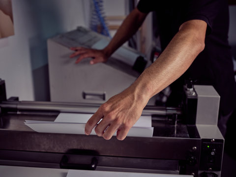 Unrecognizable worker using pressing machine in printing house