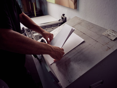 Crop faceless worker in process of book production using professional equipment in printing office