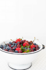 Colander Filled with Various Berries in White Tile Sink