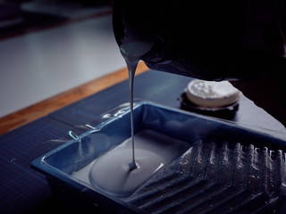 Bookbinder pouring glue into mold from square bottle
