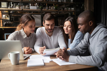 Diverse friends, students doing paperwork in cafe together