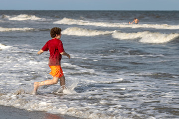 Young boy running toward ocean waves