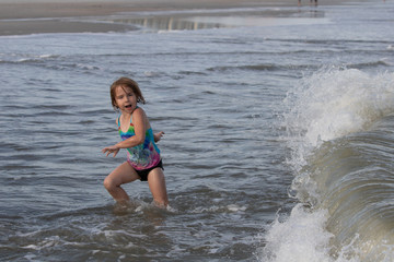 Young girl afraid of ocean wave