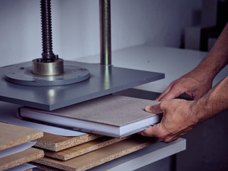 Crop anonymous employee putting book in pressing machine with screw in printing office