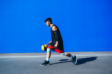 Man playing basketball in front of a blue wall