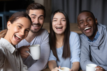 Head shot portrait of smiling diverse friends sitting in cafe together