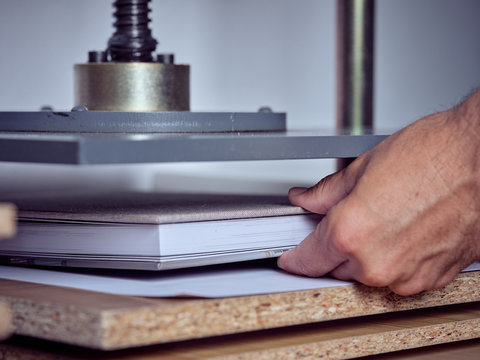 Faceless employee using pressing machine in printing office